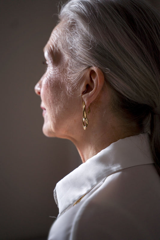 Femme élégante portant des boucles d'oreilles dorées adaptées à son âge