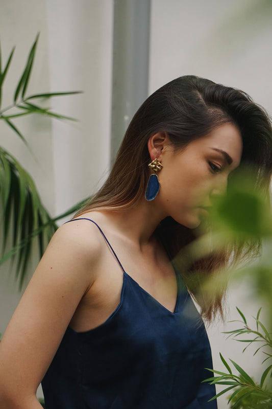 Femme portant de grandes boucles d'oreilles statement avec une tenue simple et épurée