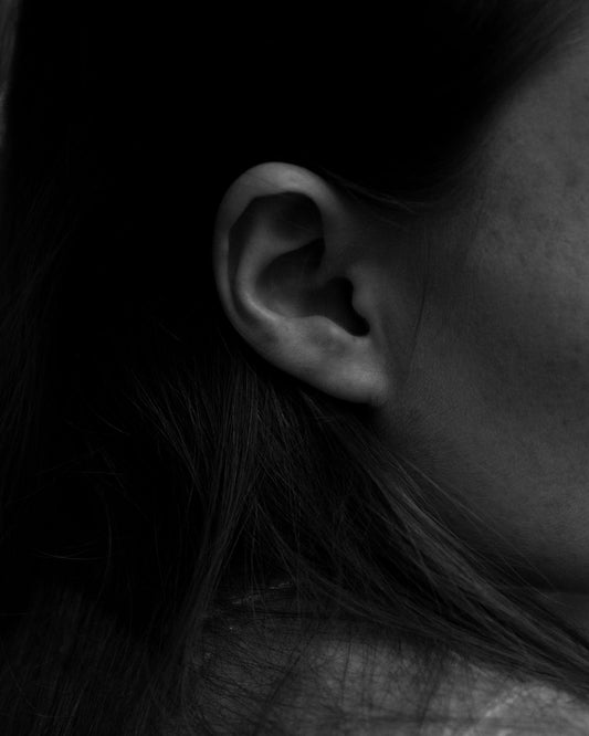 Gros plan sur l'oreille d'une femme, fond noir