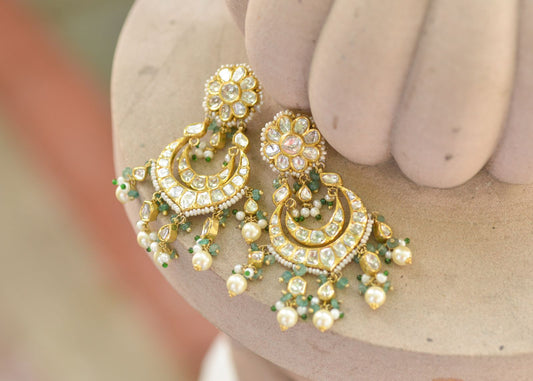 Gros plan sur des boucles d'oreilles dorées au travail artisanal soigné, illustrant le savoir-faire d'une marque française