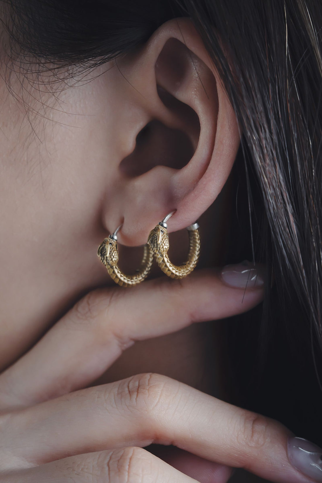 Boucles d'oreilles créoles dorées portées par une femme, style minimaliste