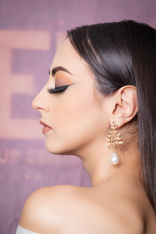 Portrait de profil d'une femme au maquillage élégant portant des boucles d'oreilles dorées