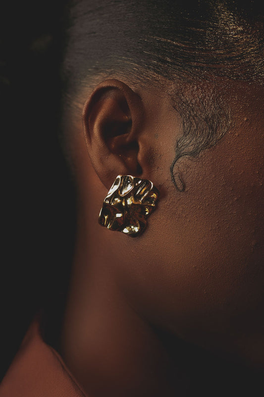 Boucle d'oreille dorée artistique sur fond sombre, ambiance soirée cocktail sophistiquée