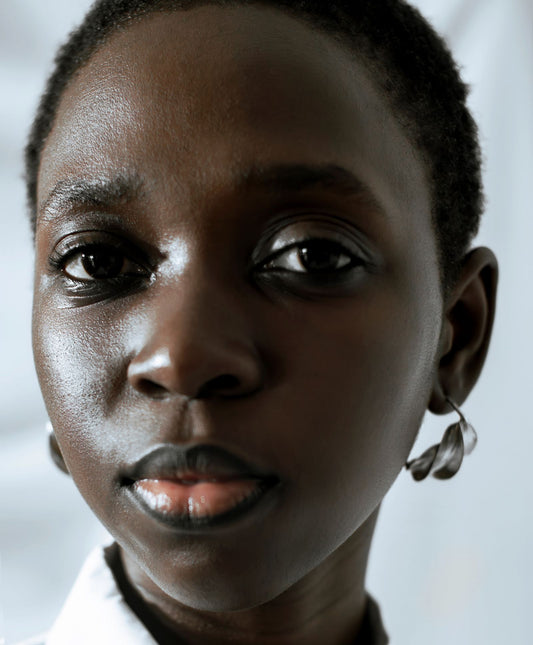 Portrait rapproché d'une jeune femme portant des boucles d'oreilles, illustrant le choix selon la forme du visage