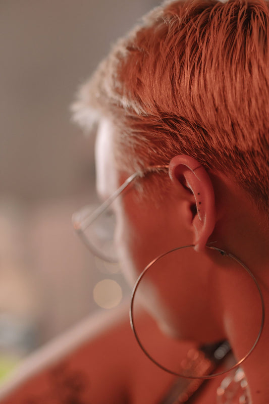 Femme aux cheveux courts blonds portant une grande boucle d'oreille créole