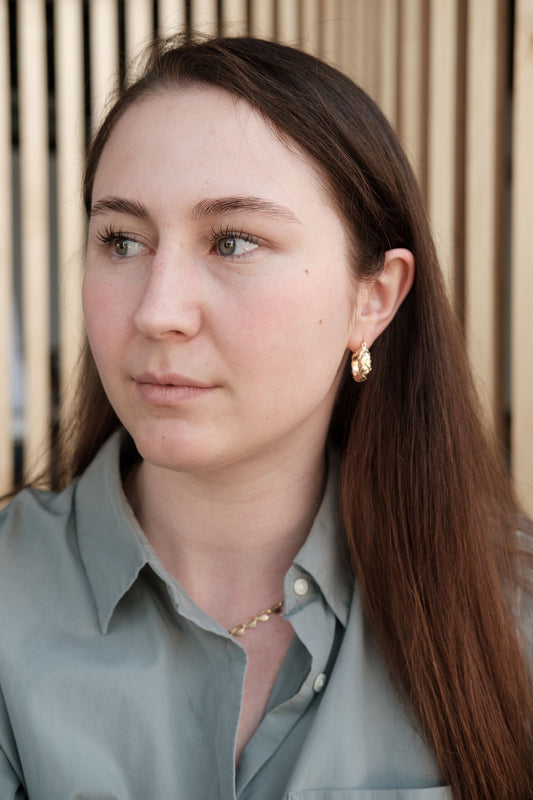 Portrait professionnel d'une femme avec de discrètes boucles d'oreilles en or, style bureau élégant