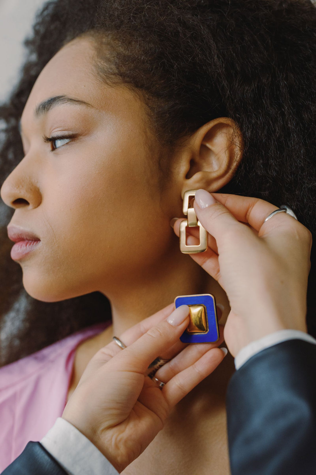 Femme essayant des boucles d'oreilles dorées géométriques